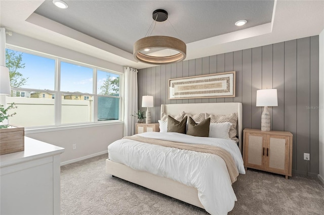 bedroom with carpet, a raised ceiling, and multiple windows