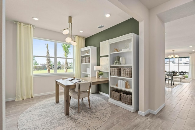 home office featuring a wealth of natural light and an inviting chandelier