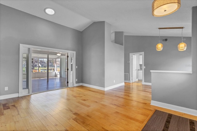 spare room featuring high vaulted ceiling and light wood-type flooring