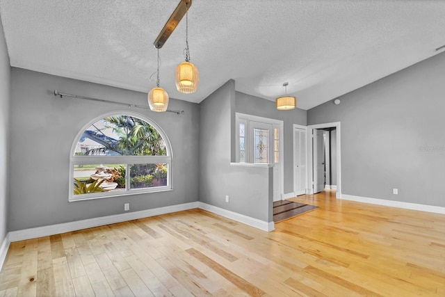 unfurnished dining area with wood-type flooring, lofted ceiling, and a textured ceiling