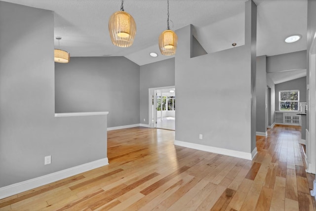 unfurnished living room with lofted ceiling, a textured ceiling, and light hardwood / wood-style flooring