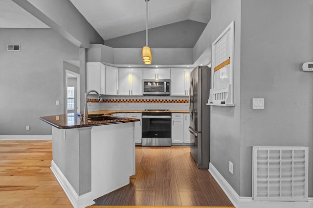 kitchen featuring appliances with stainless steel finishes, decorative light fixtures, tasteful backsplash, white cabinetry, and sink