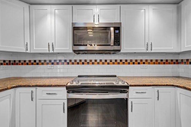 kitchen featuring appliances with stainless steel finishes, white cabinets, dark stone counters, and decorative backsplash