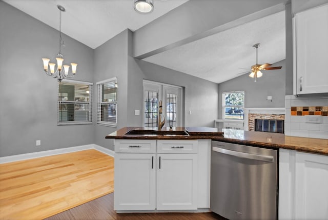 kitchen featuring ceiling fan with notable chandelier, white cabinetry, lofted ceiling, sink, and stainless steel dishwasher