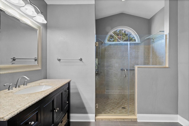 bathroom featuring vanity, a shower with door, and vaulted ceiling