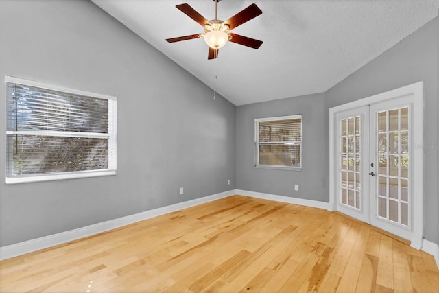 empty room with french doors, ceiling fan, lofted ceiling, and wood-type flooring