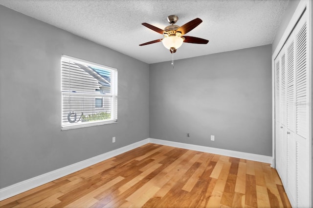 unfurnished bedroom with hardwood / wood-style flooring, a textured ceiling, ceiling fan, and a closet