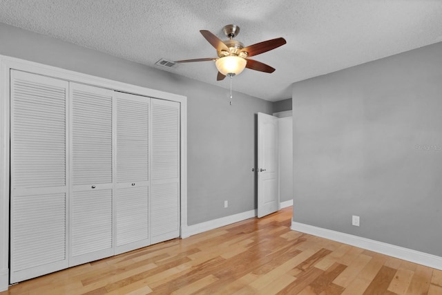 unfurnished bedroom featuring light hardwood / wood-style floors, a textured ceiling, ceiling fan, and a closet