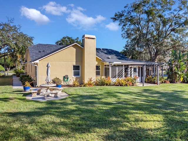 rear view of house featuring a yard, a sunroom, and a patio