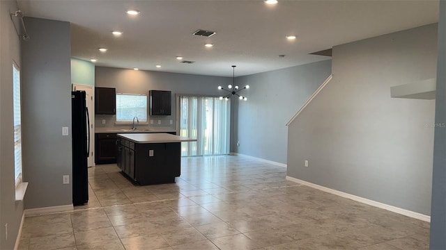 kitchen featuring sink, decorative light fixtures, a center island, black refrigerator, and a notable chandelier