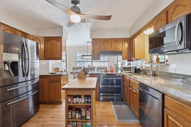 kitchen with a center island, sink, ceiling fan, light wood-type flooring, and appliances with stainless steel finishes