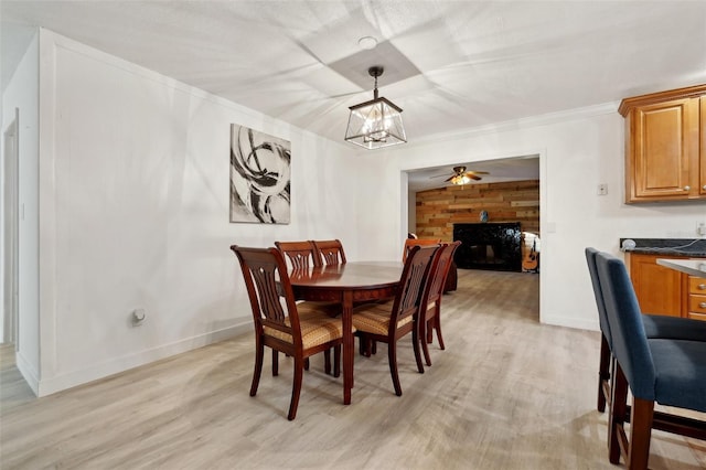 dining space featuring wood walls, ceiling fan with notable chandelier, light hardwood / wood-style floors, and crown molding