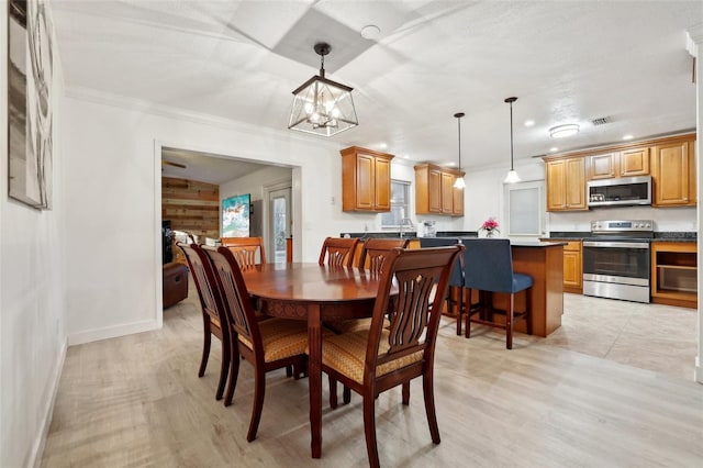 dining area featuring crown molding, light wood-type flooring, and an inviting chandelier