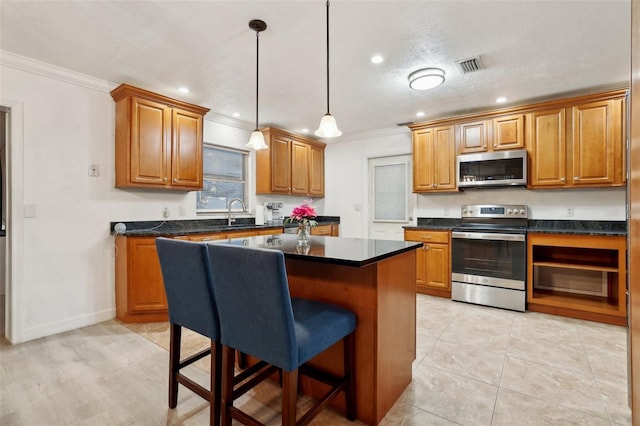 kitchen featuring stainless steel appliances, crown molding, a textured ceiling, decorative light fixtures, and a kitchen island