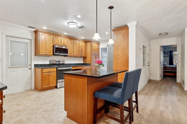 kitchen featuring ornamental molding, stainless steel appliances, pendant lighting, a kitchen island, and a breakfast bar area