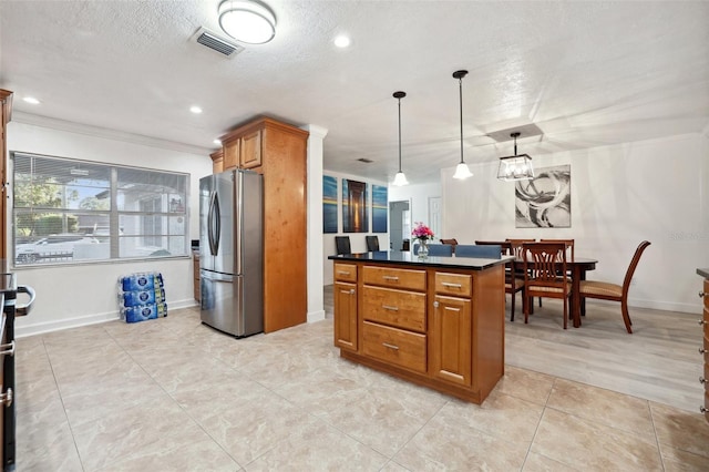 kitchen featuring crown molding, hanging light fixtures, a textured ceiling, a kitchen island, and stainless steel refrigerator