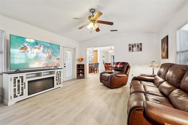 living room featuring a textured ceiling, ceiling fan, lofted ceiling, and light wood-type flooring