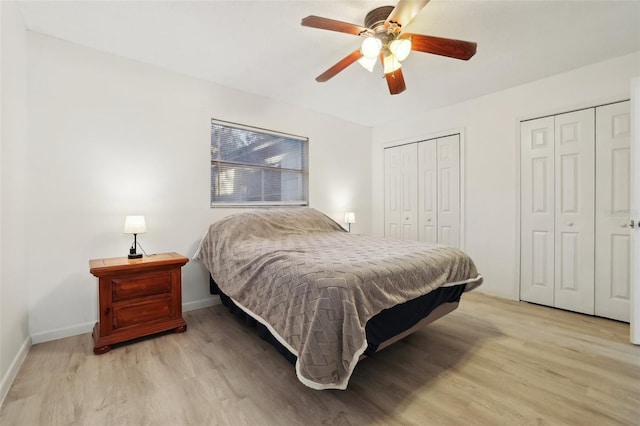 bedroom featuring light hardwood / wood-style flooring, ceiling fan, and multiple closets