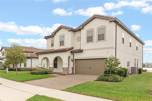 mediterranean / spanish-style home with a garage, cooling unit, and a front lawn