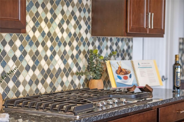 kitchen with stainless steel gas cooktop, dark stone countertops, and tasteful backsplash