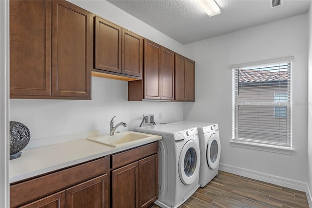 washroom featuring sink, cabinets, a textured ceiling, and washer and dryer