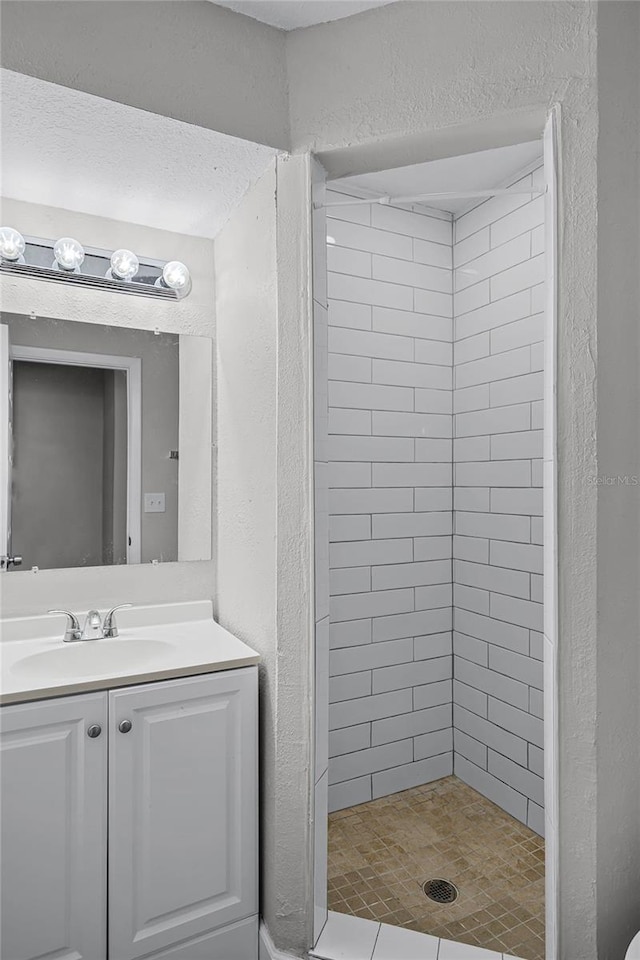 bathroom with tiled shower and vanity