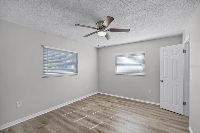 unfurnished room featuring ceiling fan, a healthy amount of sunlight, a textured ceiling, and light wood-type flooring