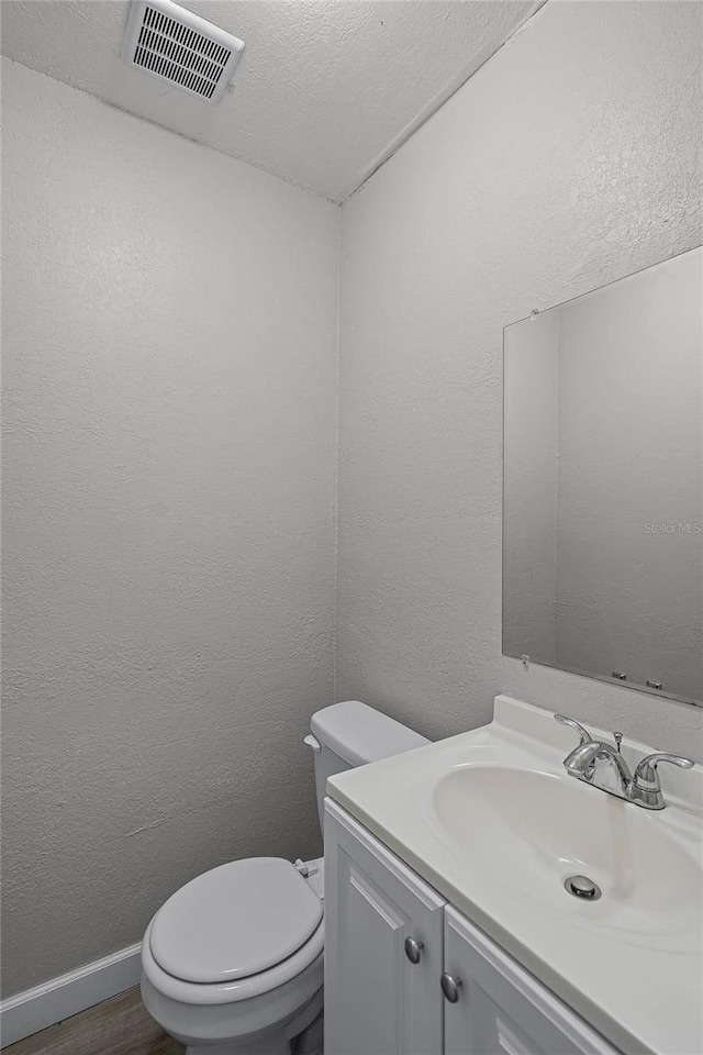 bathroom featuring wood-type flooring, vanity, a textured ceiling, and toilet