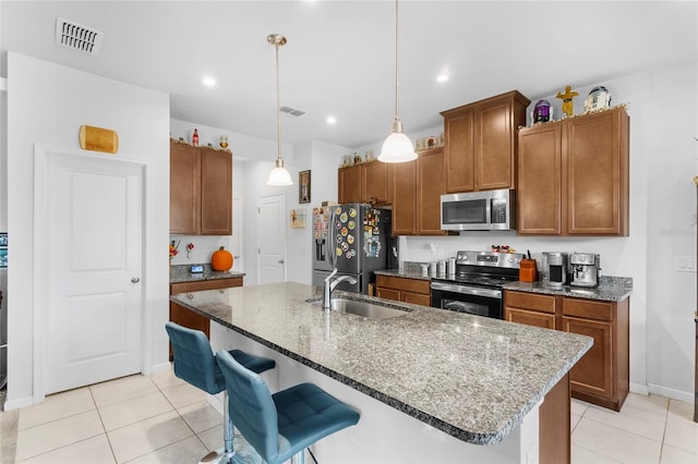 kitchen with a kitchen breakfast bar, sink, stainless steel appliances, and a center island with sink