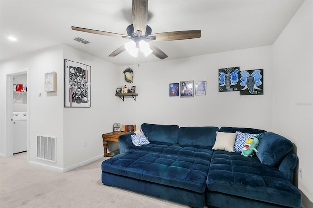 carpeted living room with ceiling fan and washer / dryer