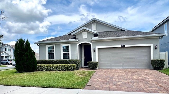 3333 Wauseon Dr, Saint Cloud, FL 34772 - view of front of house featuring stucco siding, a front yard, decorative driveway, a shingled roof, and an attached garage
