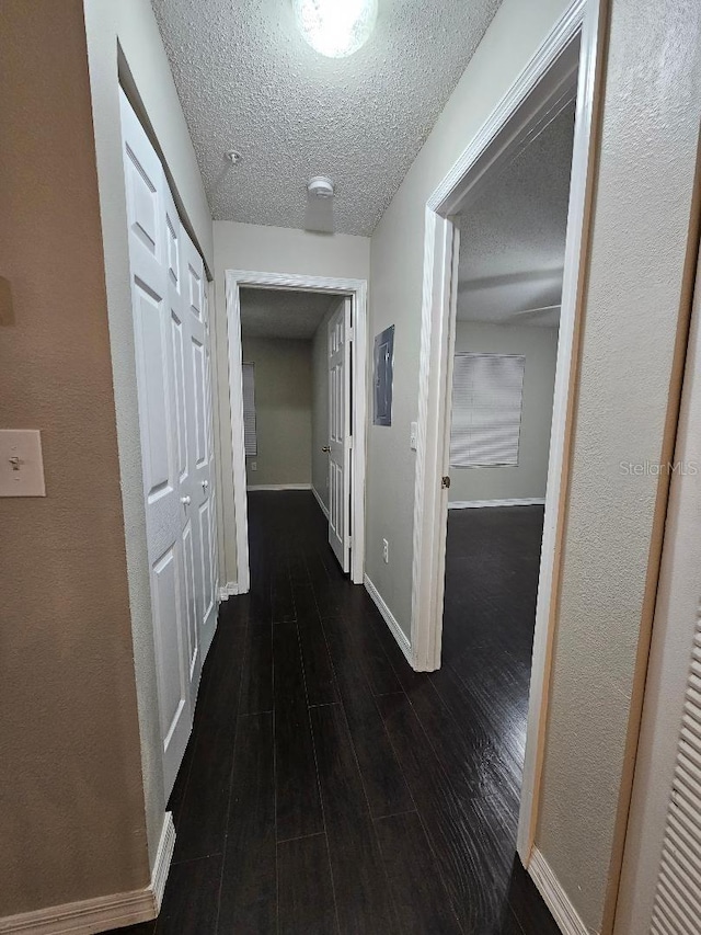 corridor with dark wood-type flooring and a textured ceiling