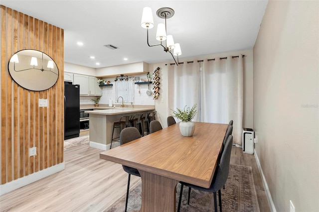 dining space featuring light hardwood / wood-style floors, a notable chandelier, and sink