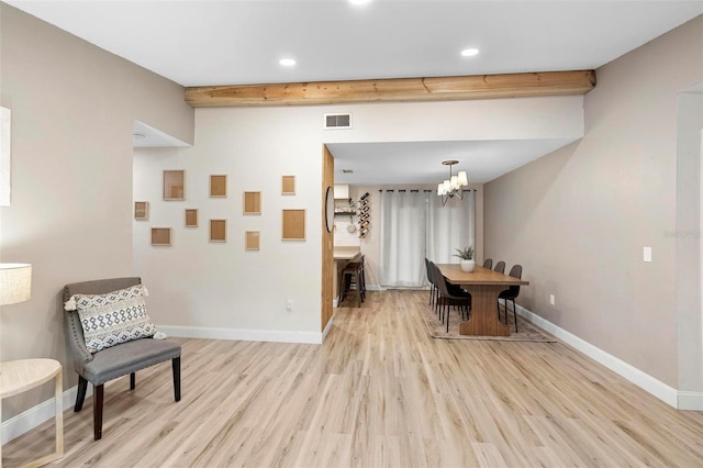 sitting room with beam ceiling, light wood-type flooring, and a chandelier