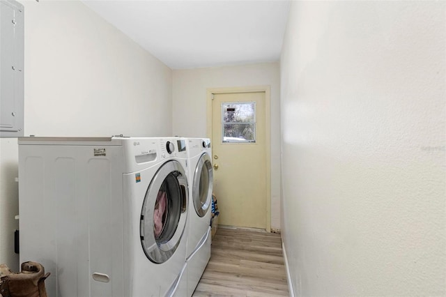 clothes washing area featuring electric panel, light hardwood / wood-style flooring, and independent washer and dryer