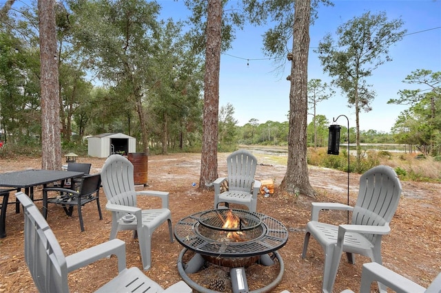 view of patio / terrace with an outdoor fire pit and a storage shed