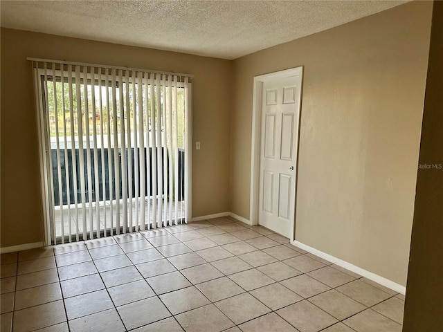 tiled empty room featuring a textured ceiling