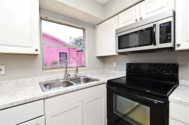 kitchen featuring black electric range, white cabinets, and sink