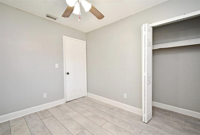 unfurnished bedroom featuring ceiling fan, a textured ceiling, and a closet