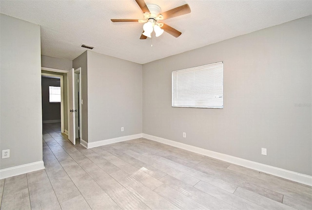 empty room featuring ceiling fan, light hardwood / wood-style floors, and a textured ceiling