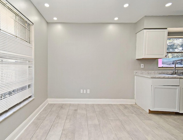 kitchen with white cabinets, light hardwood / wood-style floors, and sink