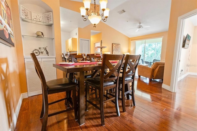 dining room with lofted ceiling, wood-type flooring, and ceiling fan with notable chandelier