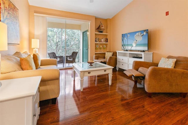 living room with hardwood / wood-style flooring, built in shelves, and lofted ceiling