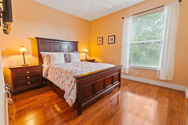 bedroom with multiple windows, ceiling fan, and dark hardwood / wood-style flooring