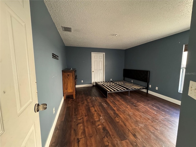 unfurnished bedroom with dark hardwood / wood-style flooring and a textured ceiling