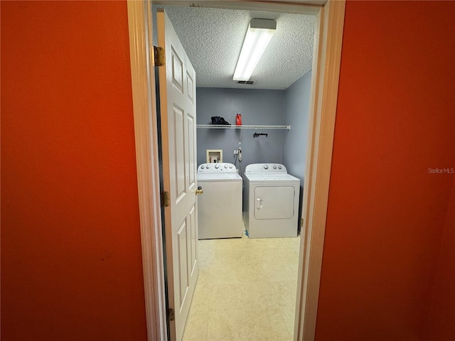 laundry room with separate washer and dryer and a textured ceiling