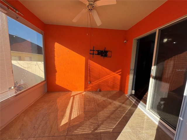 unfurnished sunroom featuring ceiling fan