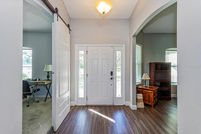 entryway with a barn door, dark hardwood / wood-style flooring, and a textured ceiling