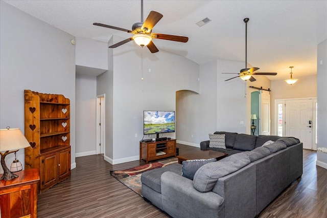 living room featuring a textured ceiling, a barn door, high vaulted ceiling, and dark wood-type flooring