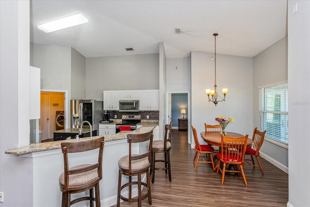 kitchen with white cabinetry, a high ceiling, backsplash, kitchen peninsula, and appliances with stainless steel finishes